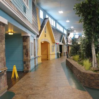A whimsical indoor pathway lined with colorful houses and greenery.