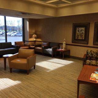 A cozy waiting room with armchairs, a sofa, and decorative artwork on the walls.