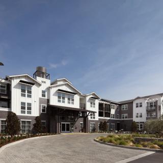 A modern residential apartment complex with landscaping and a clear blue sky.