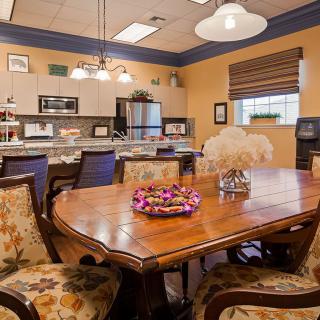 A cozy kitchen and dining area with a wooden table, floral chairs, and modern appliances.