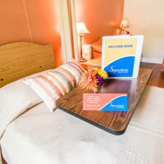 A welcoming hotel room setup with a cozy bed, decorative pillows, and a welcome card on a tray.