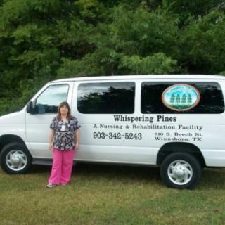 A woman standing next to a van with business signage in an outdoor setting.
