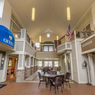 A spacious office lobby with seating area, featuring an American flag and large windows.