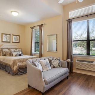 A cozy bedroom with a bed, small couch, and large window providing natural light.