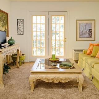 A cozy living room with elegant furniture and neutral tones, featuring a sofa, coffee table, and television.