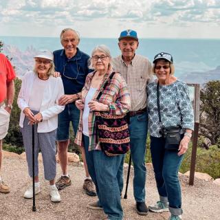 A group of seniors enjoying a day out in nature, posing together with a scenic background.