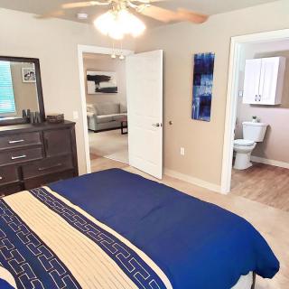 A cozy bedroom with a bed and dresser, leading to a bathroom.
