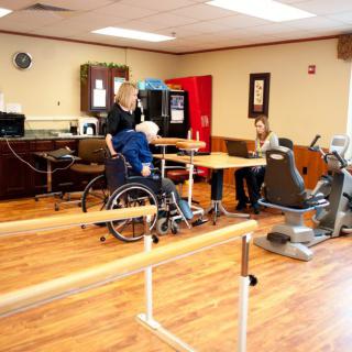 A physical therapy room with rehabilitation equipment and people engaged in various activities.