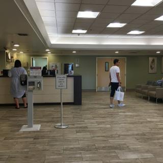 A spacious waiting area in a healthcare facility with reception desks and seating.