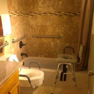 A bathroom equipped with accessibility features, including grab bars and a shower chair.