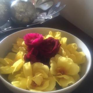 A bowl filled with vibrant yellow flowers and a red rose in the center.