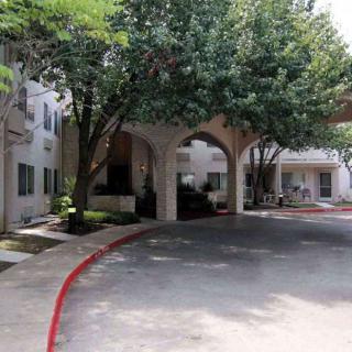 An arched entrance to a building with trees and a driveway.