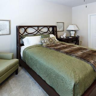 A cozy bedroom with a stylish bed featuring green bedding, complemented by decorative elements and furniture.