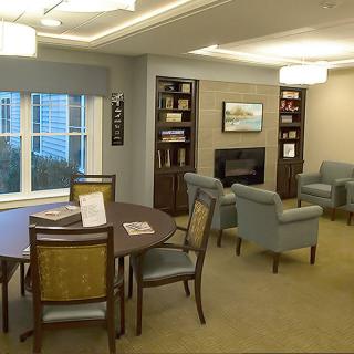 A cozy living room with comfortable seating, bookshelves, and a table near large windows.