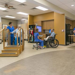 A physical therapy session in progress, showcasing medical staff assisting patients in a rehabilitation setting.