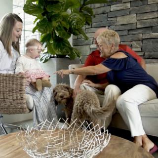 A family sitting together in the living room with their dog.