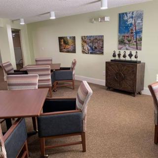 A cozy dining area with tables and chairs, decorated with artwork on the walls.