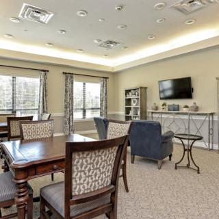 A well-furnished living room with a dining table, chairs, and a television.
