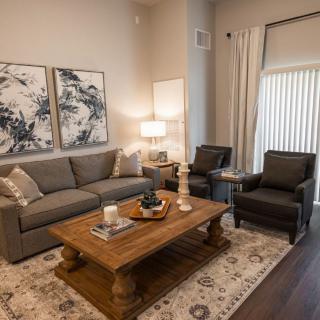 A modern living room featuring a gray sofa, two armchairs, wooden coffee table, and abstract artwork on the walls.