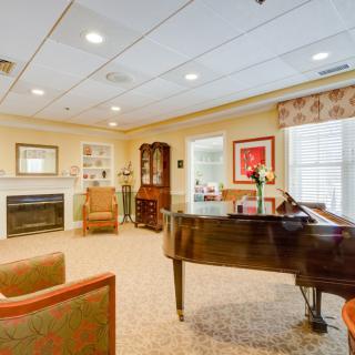A cozy living room with a grand piano, fireplace, and comfortable seating.
