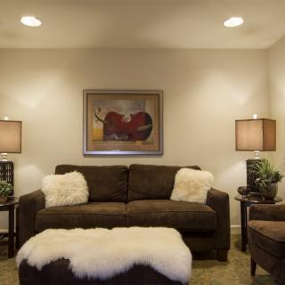 A cozy living room featuring a brown sofa and matching ottoman, complemented by soft lighting and tasteful artwork.