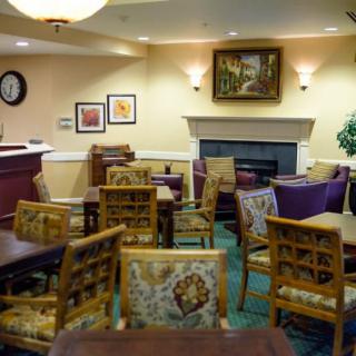 A cozy indoor cafe with tables and chairs, decorated with artwork and warm lighting.