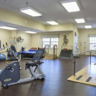 A well-equipped gym with an exercise bike and parallel bars for rehabilitation exercises.