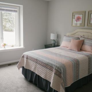 A cozy bedroom with a neatly made bed and soft lighting.