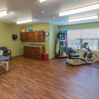 A well-equipped physical therapy room with exercise equipment and treatment tables.