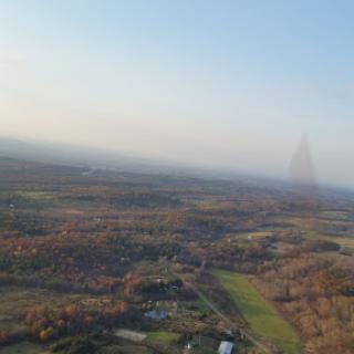 A serene aerial view of a landscape shrouded in soft fog, showcasing rolling hills and distant features.