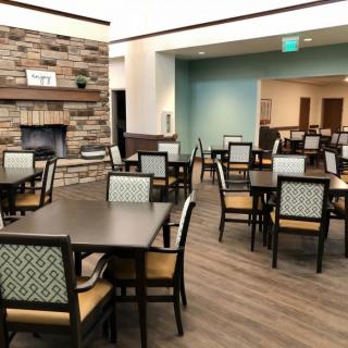 A modern dining area with neatly arranged tables and chairs, featuring a fireplace.