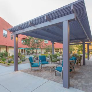 An outdoor seating area under a pergola, with patio furniture surrounded by landscaped gardens.