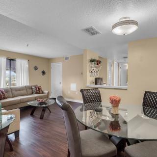 A modern living and dining area with a glass table, sofa, and wooden flooring.