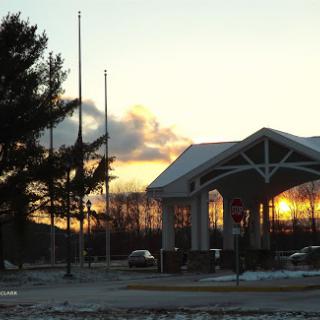 A serene sunset behind a building, with a flag at half-mast.