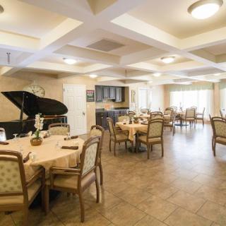 A cozy dining area with multiple tables, chairs, and a piano in the corner.