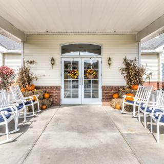A welcoming porch decorated with pumpkins and chairs, showcasing autumn decor.