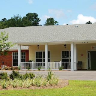 A charming single-story residential building with a welcoming porch and well-maintained landscaping.