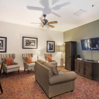 A cozy living room with comfortable seating and modern decor, featuring a television and ceiling fan.