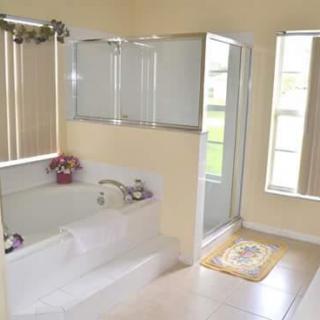 A bright and clean bathroom featuring a bathtub, shower, and large windows.