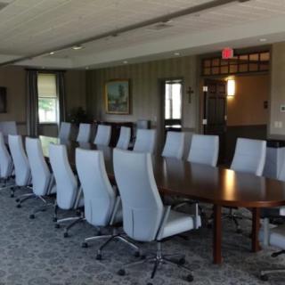 A large conference room with a long meeting table surrounded by high-backed chairs.