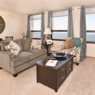 A cozy living room with a sofa, coffee table, and large windows.