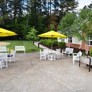 A tranquil outdoor patio area with tables, chairs, yellow umbrellas, and surrounding greenery.
