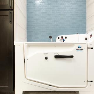 A walk-in bathtub with a door and blue tiled wall in a modern bathroom.