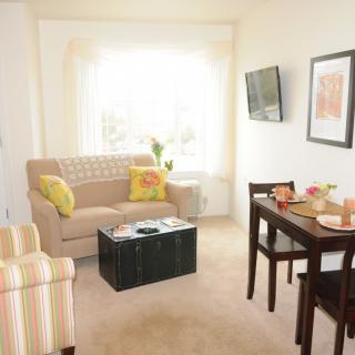 A cozy living and dining area with a sofa, table, and wall-mounted television.