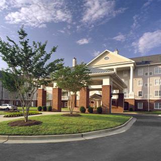 An exterior view of a hotel with well-maintained landscaping and clear skies.