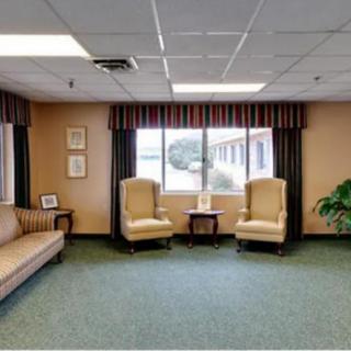 A cozy waiting room with two armchairs, a sofa, and a window providing natural light.