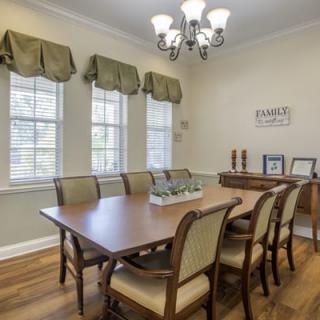 A cozy dining room with a wooden table, upholstered chairs, and a chandelier overhead.
