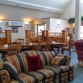 A cozy lounge area featuring a colorful striped sofa and a dining section filled with wooden chairs.