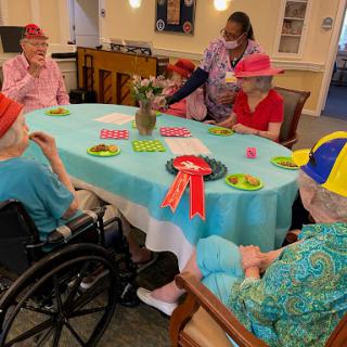 Seniors enjoying a lively game day at their community center, complete with colorful hats and engaging company.