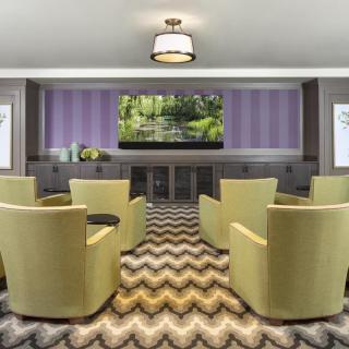 A modern conference room with green chairs and a large television.